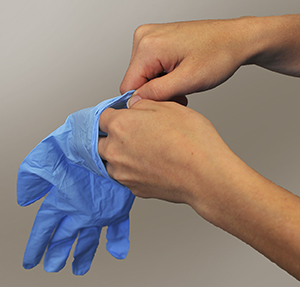 Closeup of hands putting on surgical gloves.