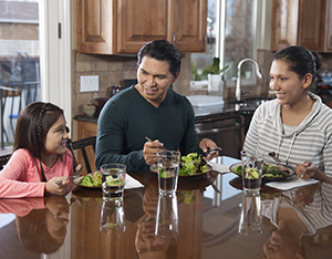 Man, woman, and girl eating healthy food at home.