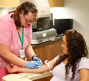 Healthcare provider drawing blood from woman's arm.