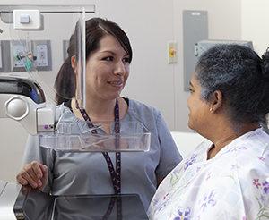 Healthcare provider preparing woman for mammogram.