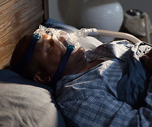 Man in bed wearing a CPAP mask.