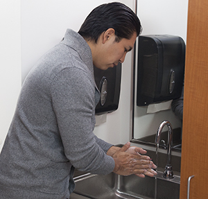 Man washing hands in hospital room.