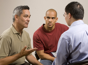 Dos hombres en una conversación grupal con un proveedor de atención médica.