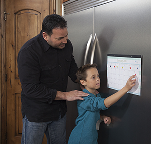 Hombre mirando a un niño mientras coloca una pegatina en el calendario.