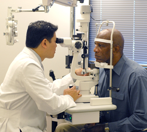 Health care provider examining man's eyes with slit lamp.